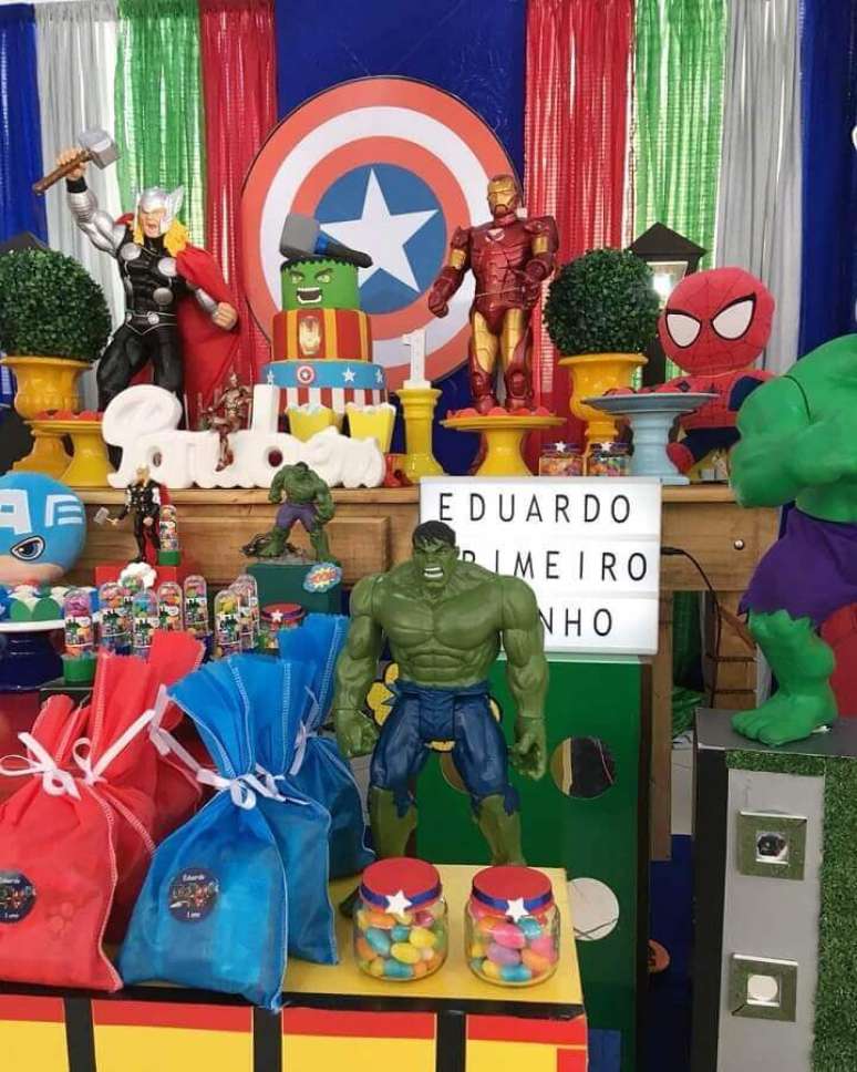 61. Ideias para festa dos Vingadores decorara com bonecos e painel com escudo do Capitão América – Foto: Peritus Festas
