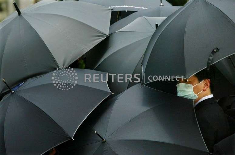 Cidadão usa máscara para evitar a Síndrome Respiratória Aguda Grave (SARS, sigla em inglês) e se esconde sob um guarda-chuva durante funeral do médico Tse Yuen-man, que contraiu a doença, em Hong Kong, China
22/05/2003
REUTERS/Bobby Yip