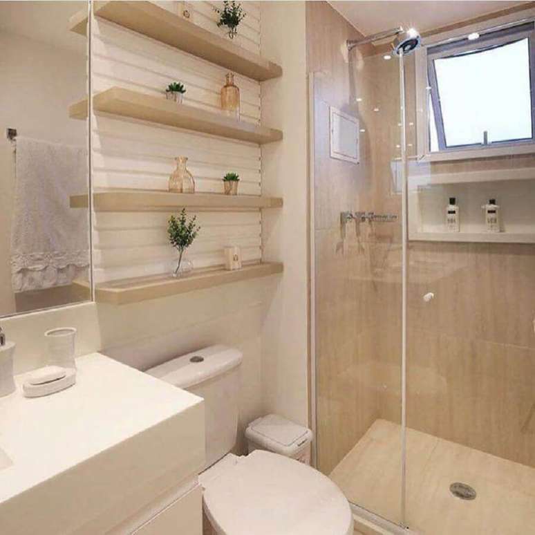 26. Decoração em tons neutros para banheiro de apartamento pequeno com prateleiras de madeira para decoração – Foto: Mônise Rosa