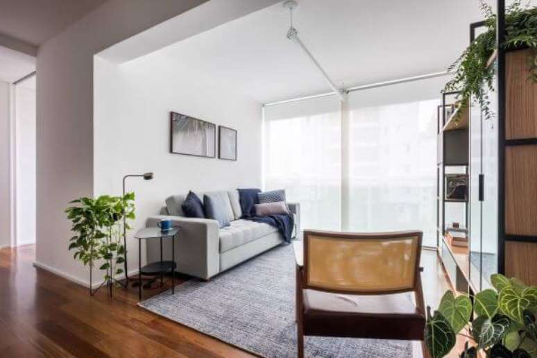 2. Sala de estar com piso laminado com rodapé branco simples – Foto: Ina Arquitetura