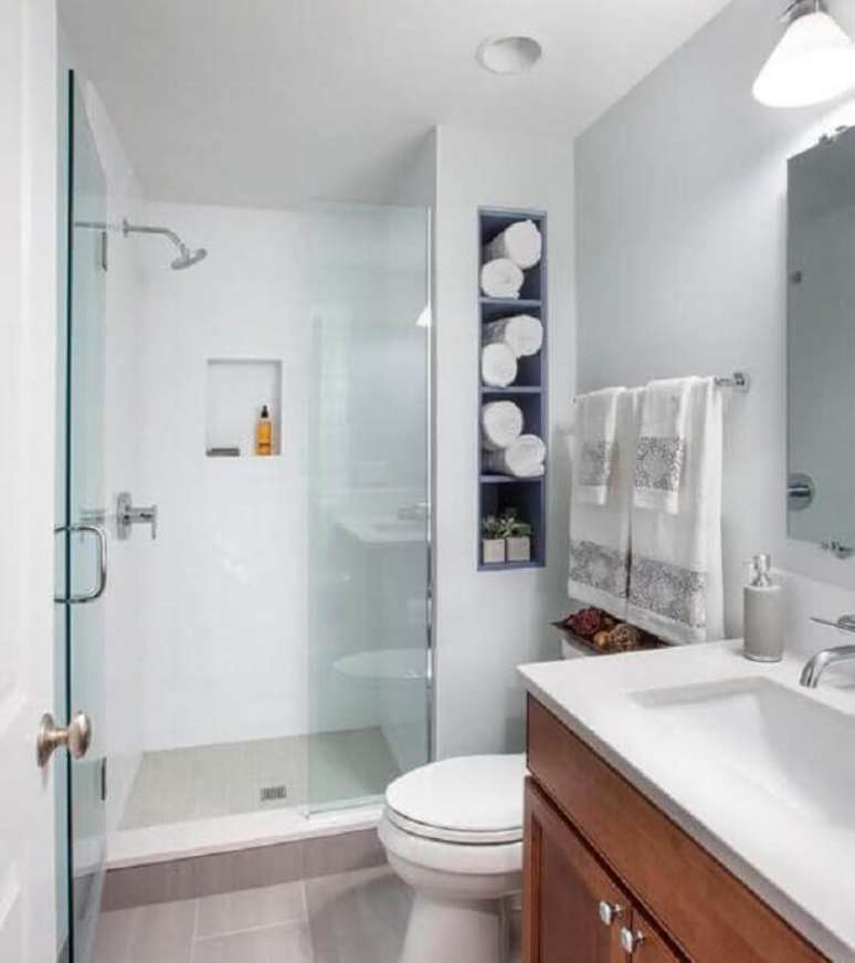 47. Modelo de banheiro de apartamento simples com nichos embutidos e gabinete de madeira – Foto: Pinterest