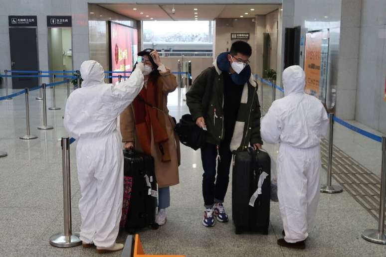 Funcionários com macacões de proteção checam a temperatura de passageiros que chegam à estação norte de Xianning, cidade próxima de Wuhan
24/01/2020
REUTERS/Martin Pollard