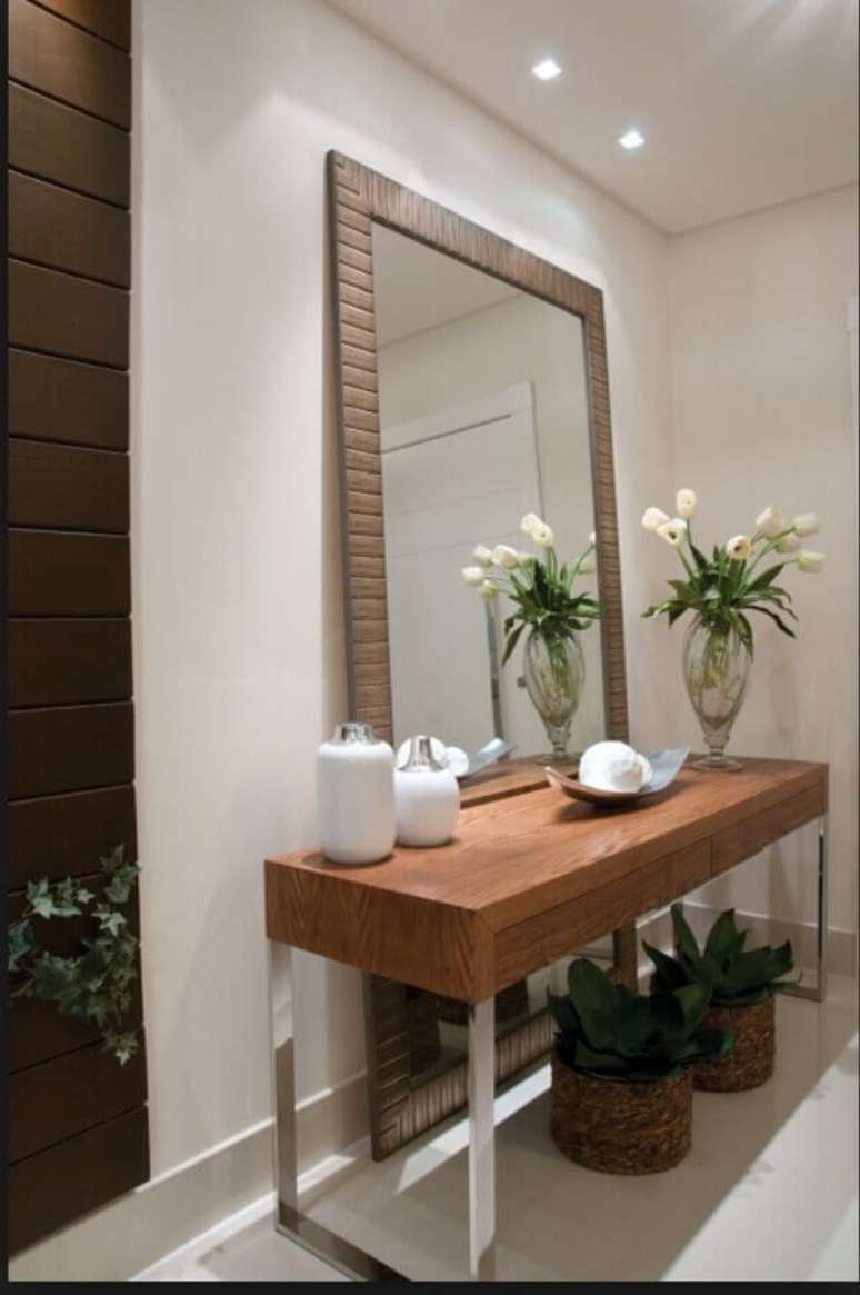 4. Decoração para hall de entrada com espelho grande de chão com moldura de madeira e aparador – Foto: Duca Móveis