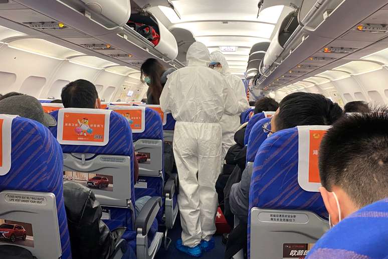 Funcionários da saúde conferem a condição dos passageiros em um avião na China