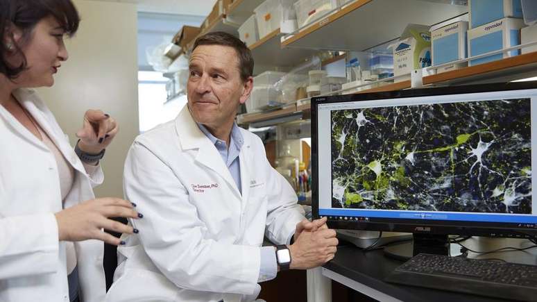 Clive Svendsen, o l&iacute;der do estudo, e a pesquisadora Nur Yucer conversam sobre imagem microsc&oacute;pica de neur&ocirc;nios produtores de dopamina