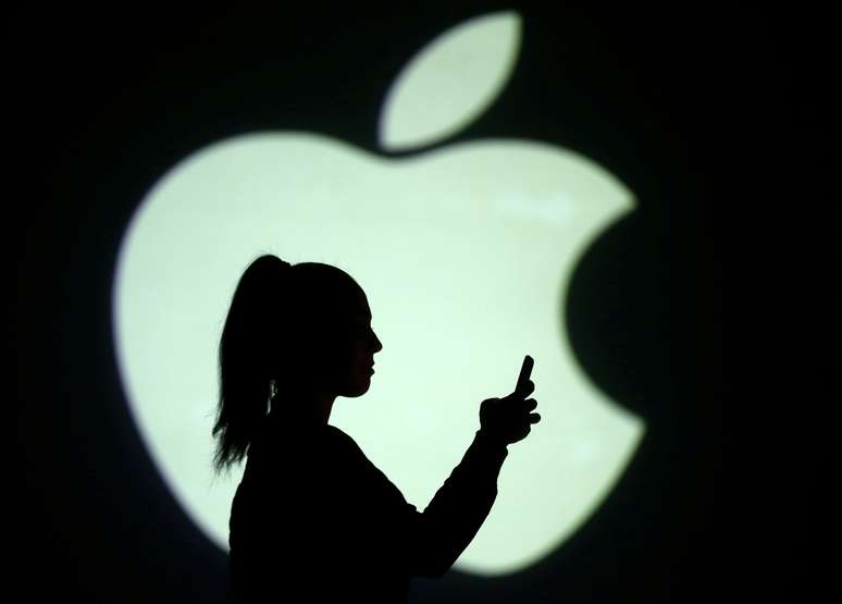 Mulher usa o smartphone em frente a projeção de uma imagem do logotipo da Apple. 28/3/2018.  REUTERS/Dado Ruvic