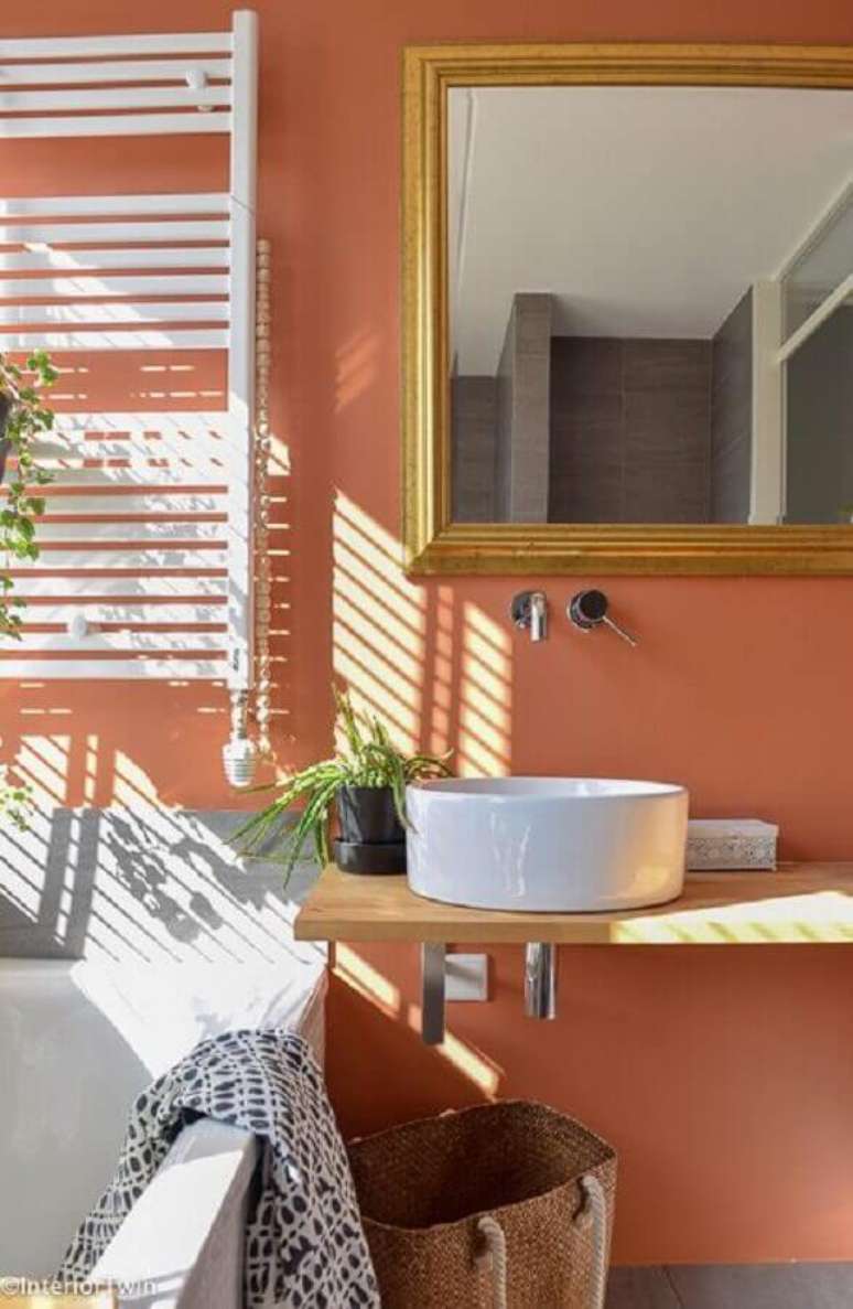 17. Cor de parede terracota para decora&ccedil;&atilde;o de banheiro com bancada de madeira &ndash; Foto: InteriorTwin