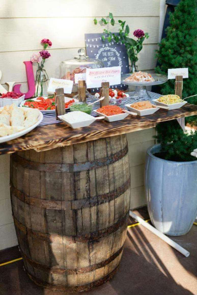 16- A decoração de noivado rústica tem barril como suporte de mesa. Fonte: Garden Decors