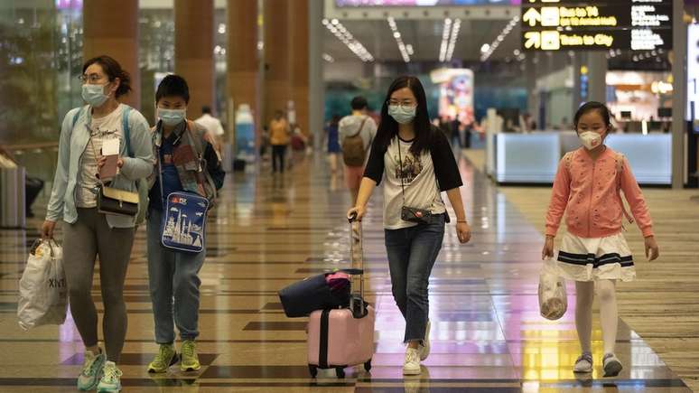 Passageiros em aeroporto de Cingapura; organismos internacionais como OMS se colocam contra medidas 'extremas' como fechamento de fronteiras e banimento de voos