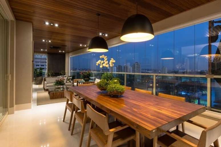 73. Para varanda cadeiras e mesas de madeira com lumin&aacute;rias de teto preta &ndash; Projeto por Mariela Uzan