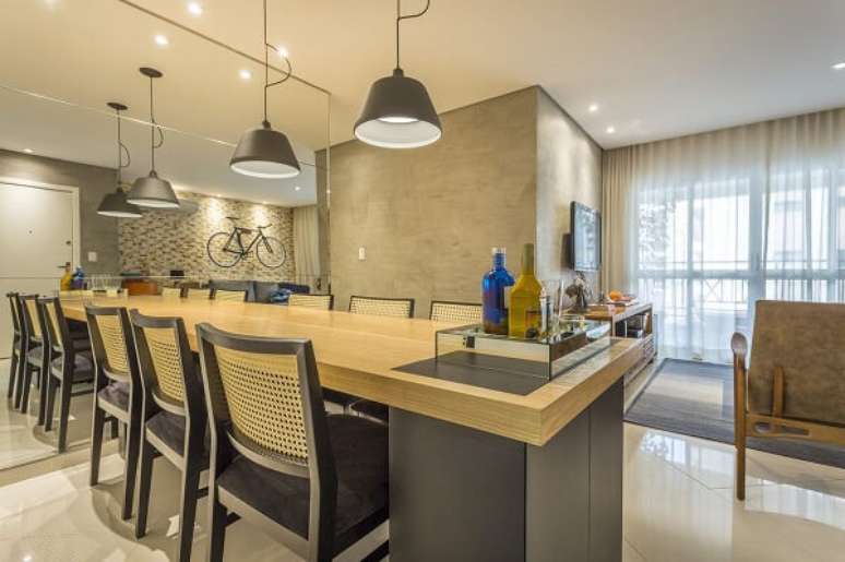 74. Para sala de jantar mesa de madeira e lumin&aacute;rias de teto &ndash; Fonte: Fl&aacute;via Campos Arquitetura