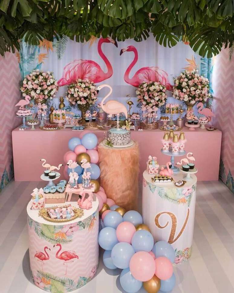 36. Decoração delicada para festa flamingo infantil azul e rosa com folhagens sobre a mesa do bolo e arranjo de rosas – Foto: Scotti Produções