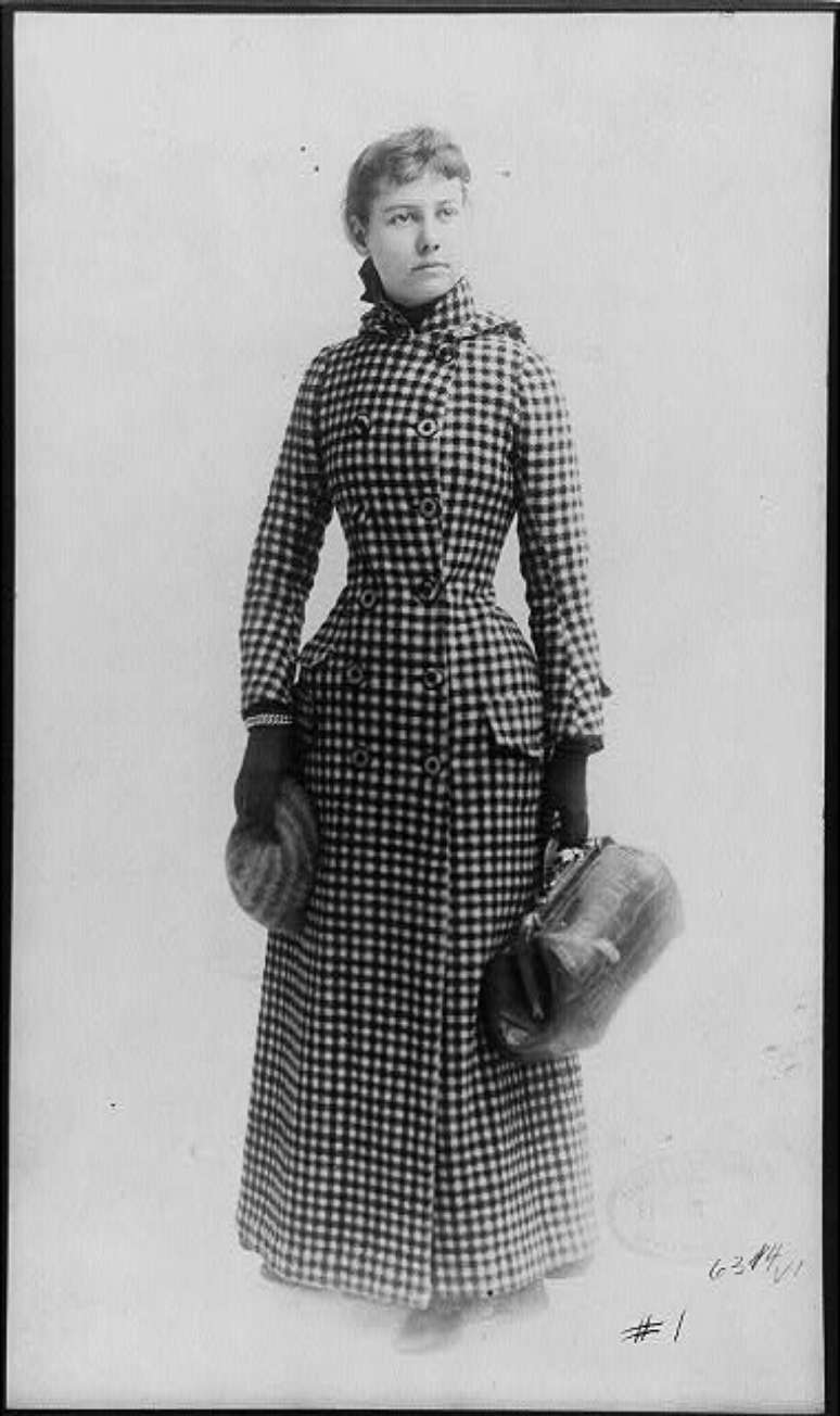 Nellie Bly com a mala de m&atilde;o que levou em sua viagem de volta ao mundo; "Mande um homem e eu come&ccedil;arei (a viagem) no mesmo dia por outro jornal e vou derrot&aacute;-lo", disse Bly a seu editor