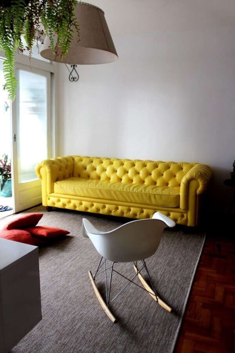 28. Sala de estar com sofá amarelo chesterfield e cadeira de balanço Eames branca. Fonte: Pinterest