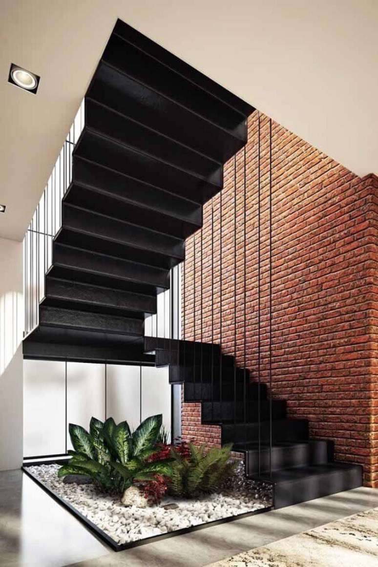 2. A decoração moderna com a escada na cor preta ganhou um toque rústico e acolhedor com a parede de tijolo à vista – Foto: Webcomunica