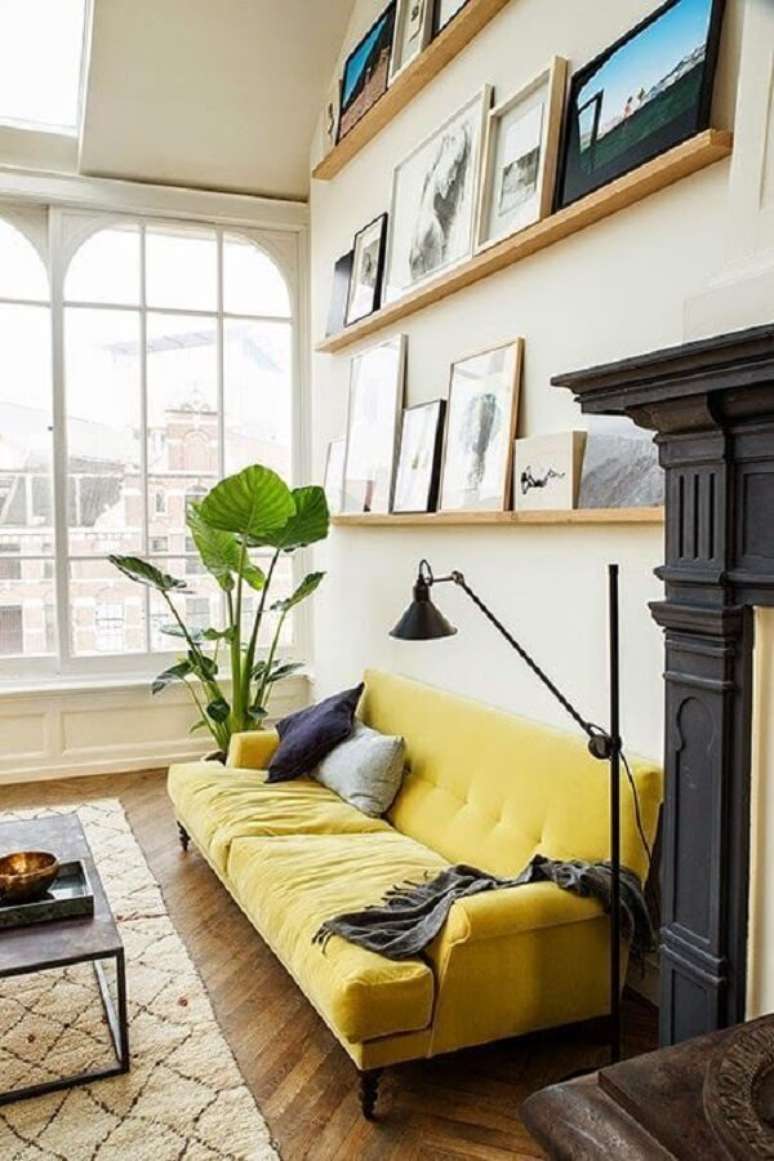 35. Sala de estar com sof&aacute; amarelo e prateleiras para quadros. Fonte: Pinterest