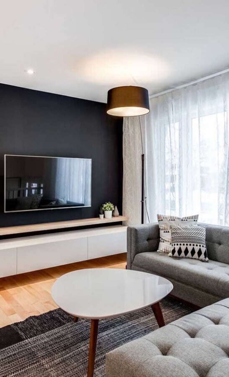 62. Parede na cor preta para decoração de sala de estar com sofá cinza e piso de madeira – Foto: Ideias Decor