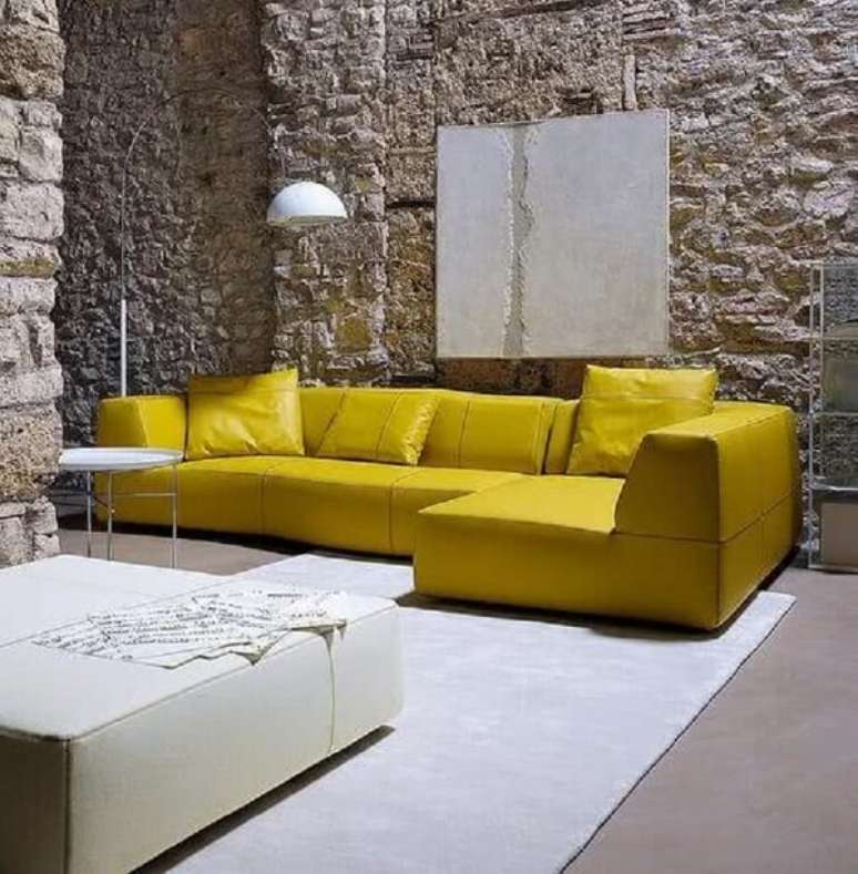 53. Sala de estar com parede de pedra e sofá amarelo de canto. Fonte: Pinterest