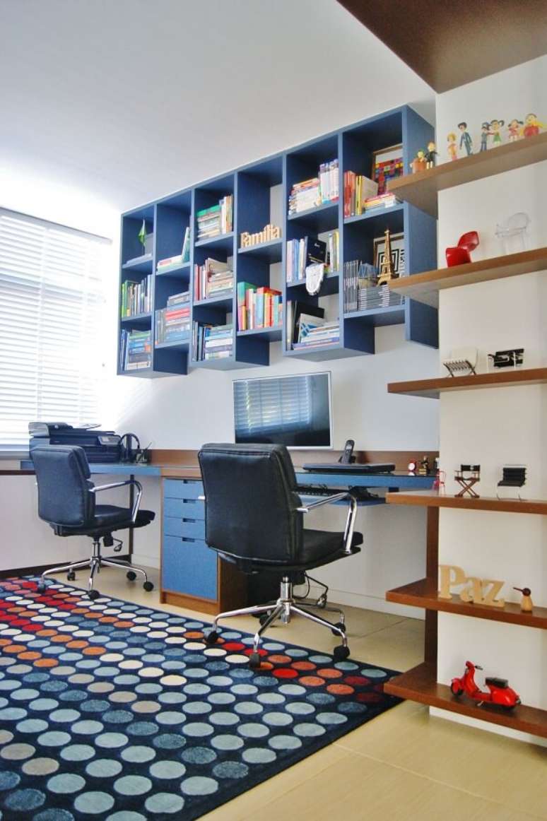 18. Escrit&oacute;rio planejado com tapete colorido, cadeiras de rodinha e nichos em tom azul. Projeto por Priscila Fernandes Arquitetura