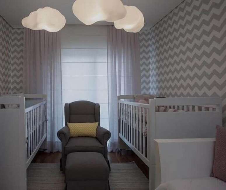 25. Decora&ccedil;&atilde;o de quarto de beb&ecirc; g&ecirc;meos com papel de parede zigue zague e lumin&aacute;rias em formato de nuvem