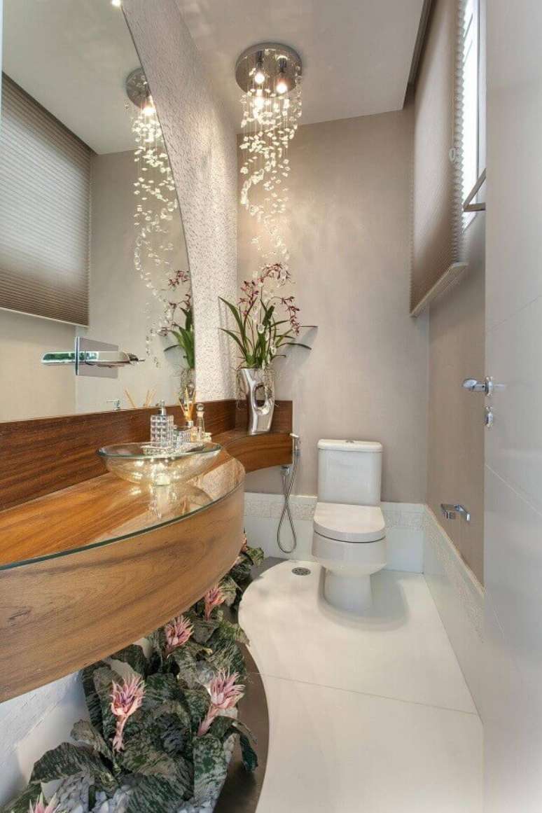 32. Decoração sofisticada com lustre de cristal e bancada de madeira para banheiro com cuba de vidro – Foto: Webcomunica