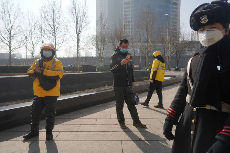 Entregadores da Meituan ao lado de um oficial de seguran&ccedil;a em um shopping center ap&oacute;s o feriado prolongado do Ano Novo Lunar causado pelo novo surto de coronav&iacute;rus, na China. 10/2/2020. REUTERS/Stringer