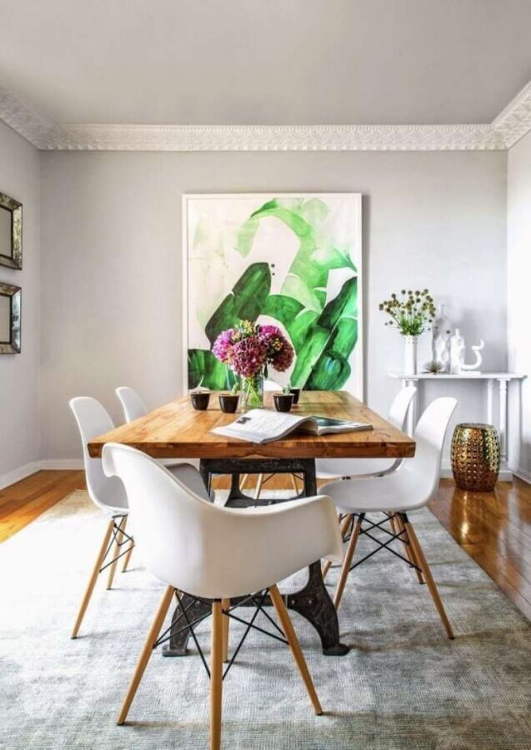 56. Mesa com cadeira branca eames para decoração de sala de jantar com tapete cinza e quadro grande – Foto: Pinterest