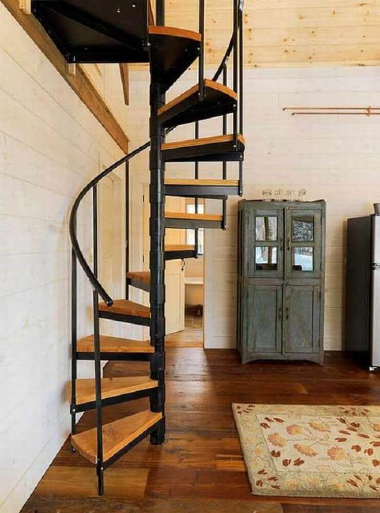 7. Casa com escada caracol de ferro com degraus de madeira.