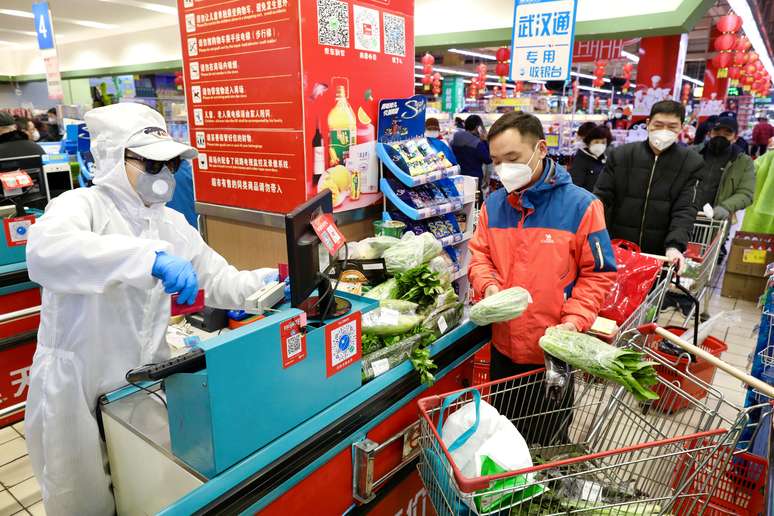 Funcionário em roupas de proteção serve a clientes em mercado de Wuhan, na China
12/02/2020
China Daily via REUTERS