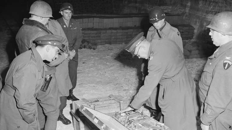 Militares americanos do comando aliado examinam mala de talheres de prata, parte do saque alemão armazenado em uma mina de sal em Merkers
