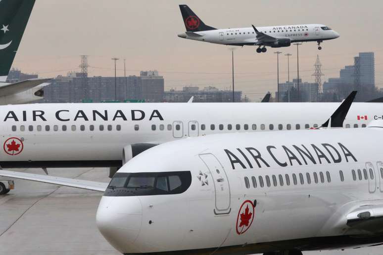 Duas aeronaves Boeing 737 MAX 8 [aradas em aeroporto, enquanto um jato da Embrer voa ao fundo. 13/3/2019.  REUTERS/Chris Helgren 