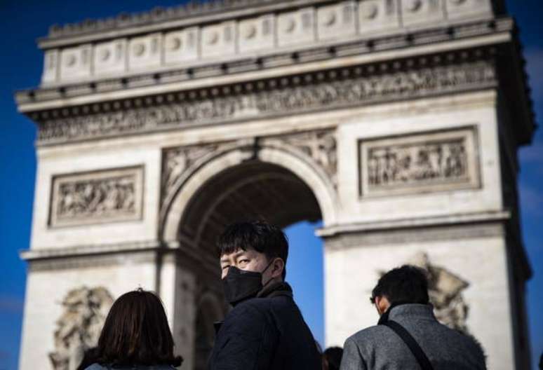 Turistas com máscaras de proteção em frente ao Arco do Triunfo, em Paris
