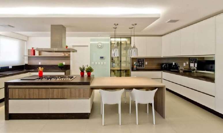 26. Decoração moderna para cozinha planejada com cooktop e bancada de madeira ligada à ilha – Foto: Espaço do Traço