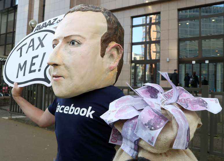 Um ativista usando máscara em referência ao presidente do Facebook, Mark Zuckerberg, protesta pedindo aumento de impostos sobre a empresa. 4/12/2018. REUTERS/Yves Herman