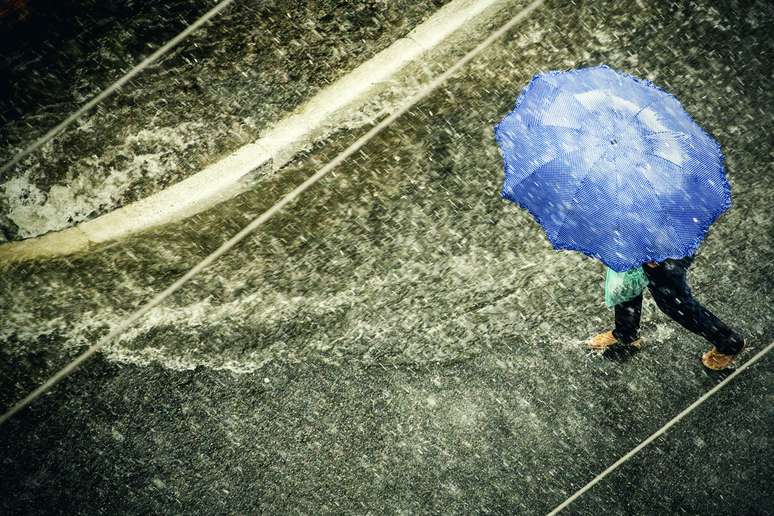 Pedestres se protegem de chuva forte no final da tarde dessa terça-feira.