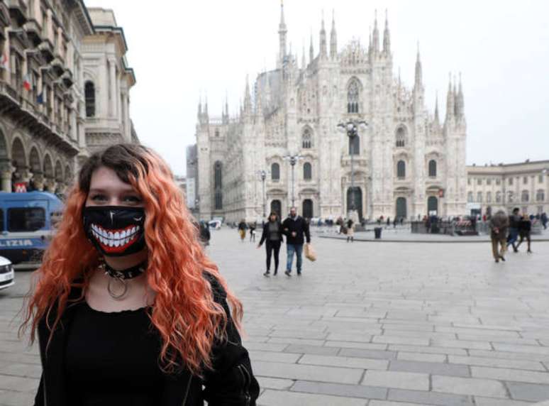 Jovem usando máscara em frente à Catedral de Milão, no norte da Itália