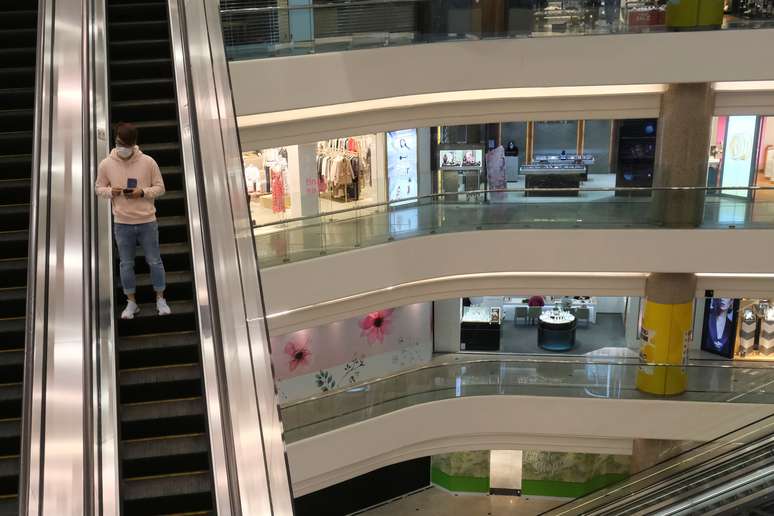 Homem usando máscara de proteção desce na escada rolante de um shopping center. 21/2/2020. REUTERS/Tyrone Siu