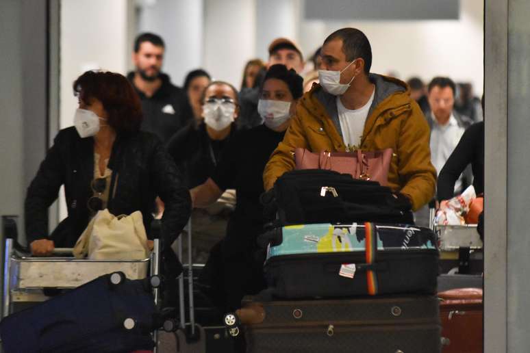 Passageiros de voo da Companhia Aérea Alitalia, vindo de Roma, desembarcam no Aeroporto Internacional de Guarulhos usando máscaras.