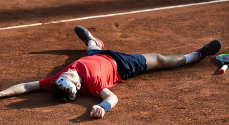 Thiago Wild se joga na quadra de saibro após bater norueguês Casper Ruud por 2 sets a 1 (Crédito: Jim Rydell/AFP)