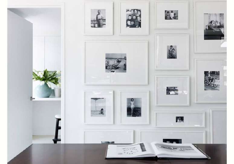 13. Decoração minimalista com mural de fotos na parede com molduras brancas minimalistas e fotos em preto e branco