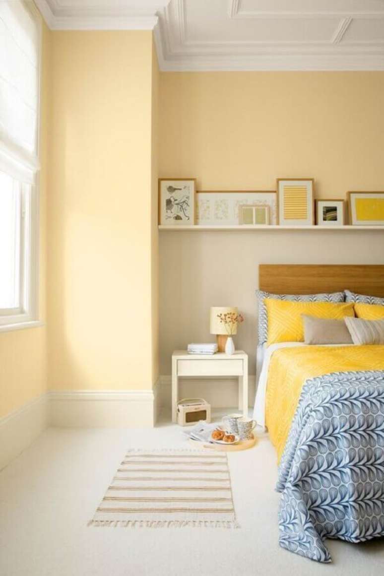 13. Decoração clean de quarto amarelo claro com cabeceira de madeira – Foto: A Casa Perfeita