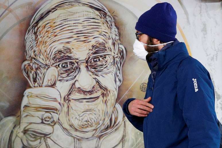 Homem com máscara passa por mural representando o papa Francisco
13/03/2020
REUTERS/Guglielmo Mangiapane