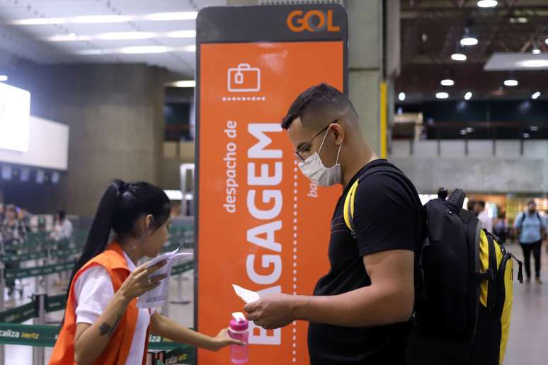 Homem usando m&aacute;scara de prote&ccedil;&atilde;o faz check in com funcion&aacute;ria da Gol, durante epidemia do coronav&iacute;rus. 12/3/2020. REUTERS/Rahel Patrasso 