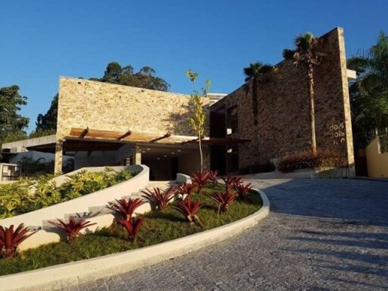 95. Fachada de casa moderna com revestimento de pedra e pergolado de madeira – Foto: C2HA Arquitetos