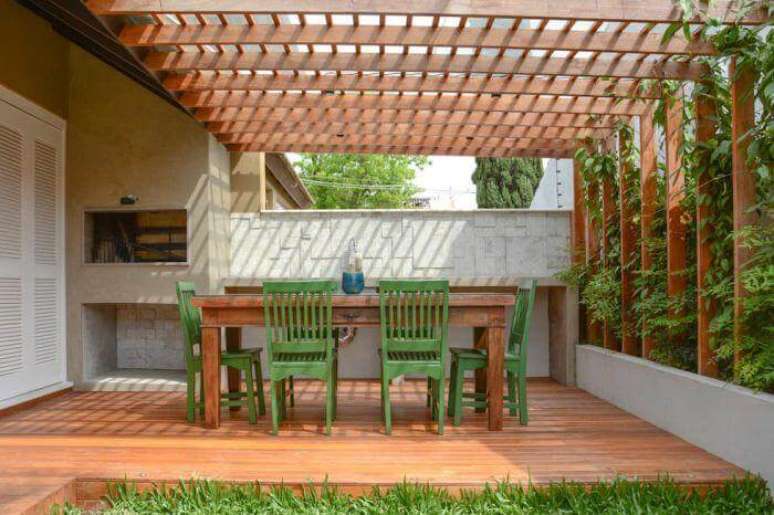 84. Decoração com pergolado de madeira combinando com piso e mesa de varanda com jardim vertical – Foto: Haus Best