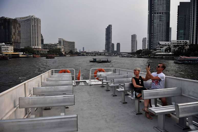 Um casal anda de barco em um passeio turístico no rio Chao Phraya em Bangkok, Tailândia, onde o número de visitantes caiu drasticamente