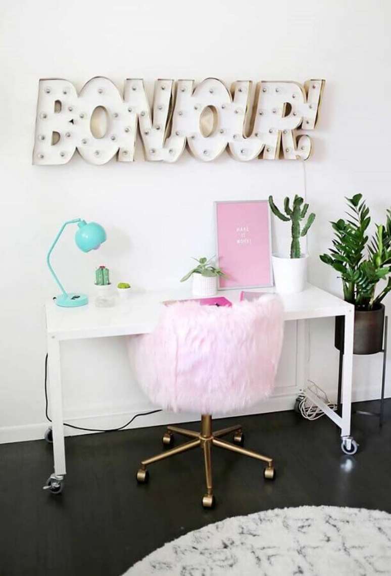 56. Delicada decoração de home office feminino com luminária azul Tiffany e cadeira rosa com tecido de pelinhos – Foto: A Beautiful Mess