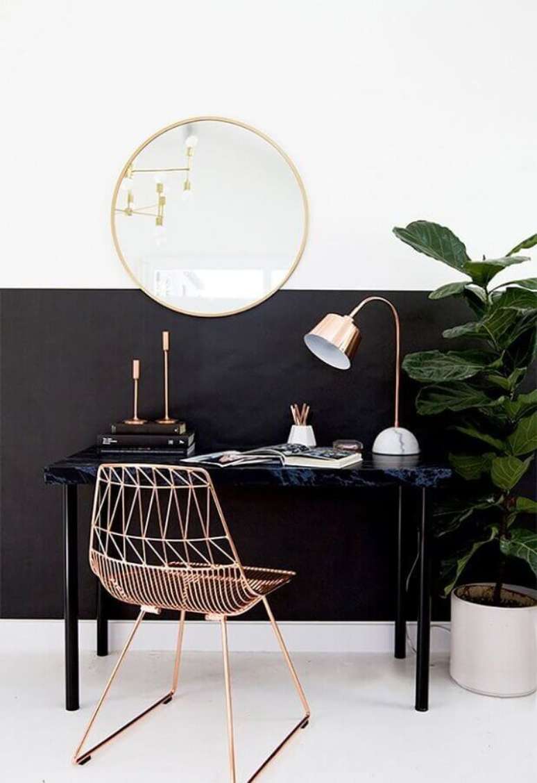 57. Home office decorado com parede preta e branca e cadeira aramada rose gold e espelho redondo – Foto: Pinterest