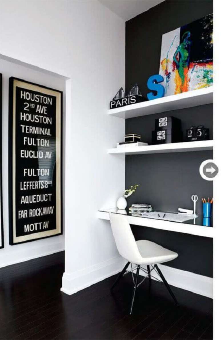 58. Home office decorado com parede preta e prateleiras e bancada branca – Foto: Achados de Decoração