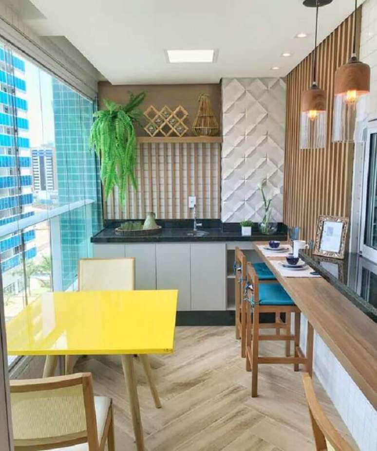 12. Apartamento com área gourmet pequena e simples decorada com mesa amarela e banqueta azul – Foto: Dicas de Mulher